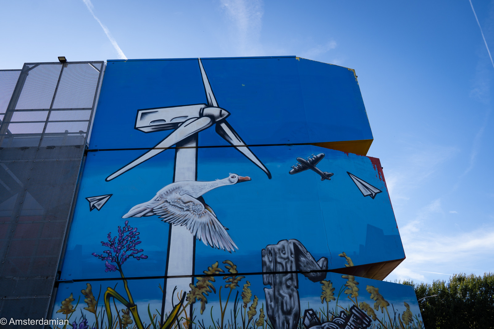 Almere mural of a wind turbine, a goose and planes against a blue sky