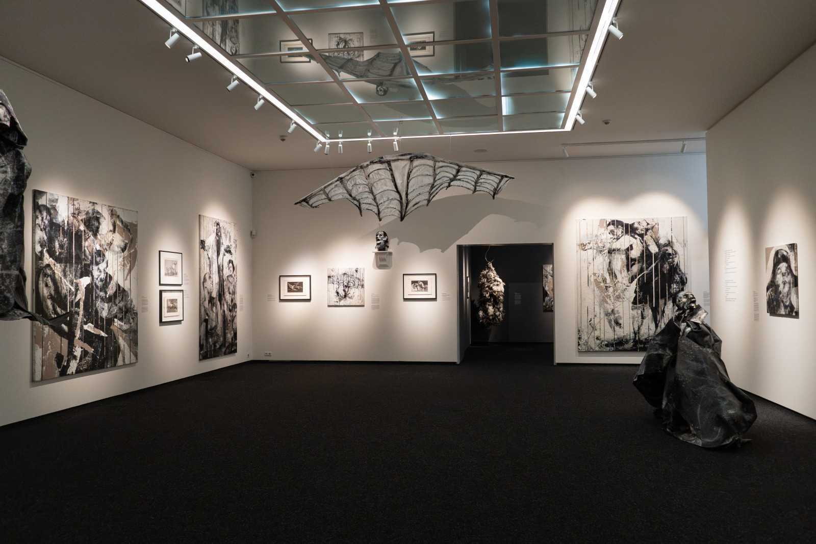 Large black-and-white paintings and a winged sculpture at Museum JAN