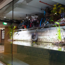 Amsterdam canal exhibit at ARTIS Aquarium - rusty bicycles resting above a canal-wall tank