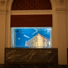 Marble-framed aquarium windows in the historic hall, the middle tank holding a shipwreck