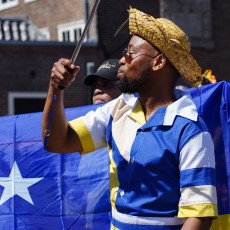 Man in a blue and yellow costume with a sabre at the Bigi Spikri parade, Amsterdam