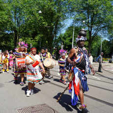 Bigi Spikri parade crossing an Amsterdam street with drummers and dancers