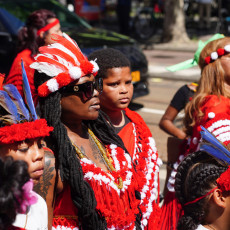 Participants in red and white feather headdresses at Bigi Spikri, Amsterdam