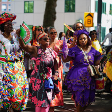 Women in koto dress waving hand fans at the Bigi Spikri parade, Amsterdam