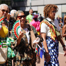 Parade-goers waving fans in colourful dress at Bigi Spikri, Amsterdam