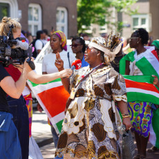 A TV crew films a participant at the Bigi Spikri parade, Amsterdam, on Keti Koti