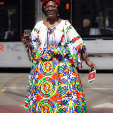 Woman in a vibrant koto dress and headwrap at the Bigi Spikri parade, Amsterdam