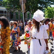 Participant in a white koto dress among the Bigi Spikri crowd, Amsterdam