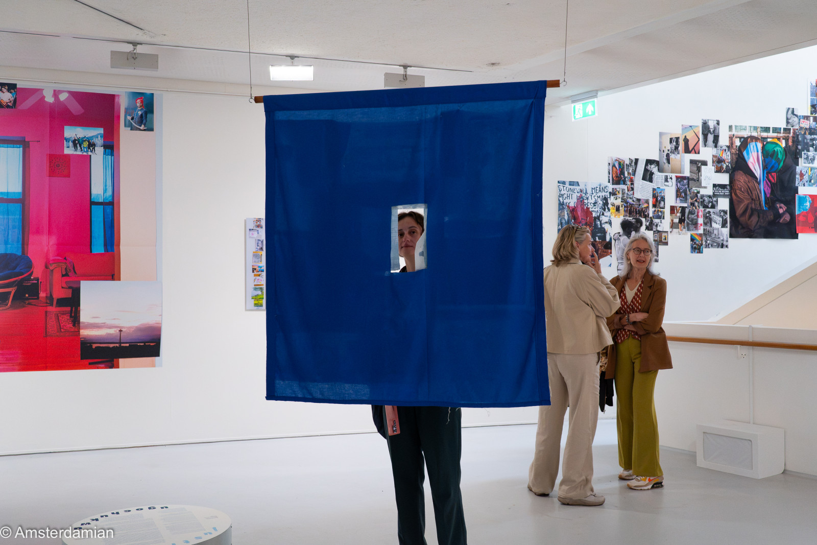 Visitor peeking through a hole in a hanging blue cloth, Fotomuseum Hilversum