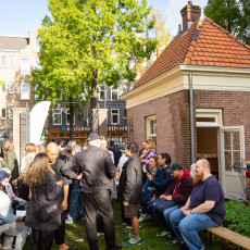 A group of people filling the courtyard at IN DE KOST event at De Poorthuisjes