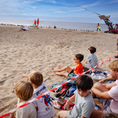 Children sitting on the sand watching the kite festival