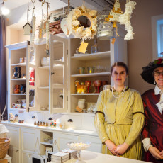 Two shopkeepers in Victorian costume behind the counter of a De Rijp gift shop