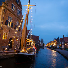 A traditional sailing barge lit up beside the 1630 town hall on the De Rijp canal