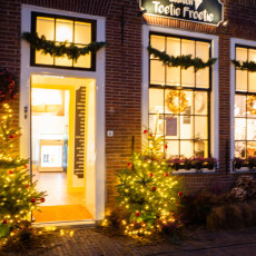 Lit Christmas trees flanking the door of the Toetie Froetie shop in De Rijp