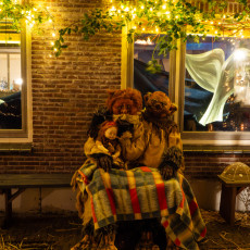 Performers in bear costumes on a bench in front of painted whale-tail windows