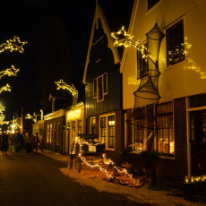 Lit fish traps and branches along a narrow street in De Rijp after dark