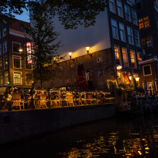 Lit canalside terrace at night, from a boat in Amsterdam