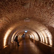 Vaulted brick corridor in the cellars of Het Scheepvaartmuseum, lit along the walls