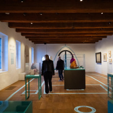 Archaeology gallery with glass display tables under heavy wooden ceiling beams
