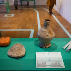 Stoneware jug and net weights recovered from shipwrecks, shown in a display case