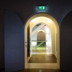 Open doors leading to a softly lit stairwell inside Het Scheepvaartmuseum