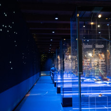 Blue-lit gallery of navigation instruments in glass cases at the maritime museum