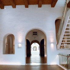 White hall and staircase with an archway through to the museum courtyard
