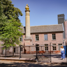 A stone column beside a low brick building in Tilburg