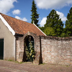 Small white-gabled building beside an old brick wall in Veere