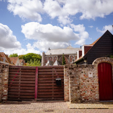 Brick garden walls with a red door and the church behind, Veere