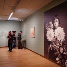 Wall-sized photograph of a young Yayoi Kusama holding flowers