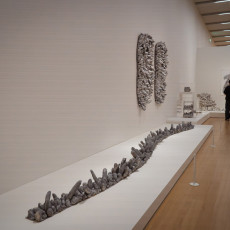 A line of Kusama's soft sculptures stretching along a white plinth