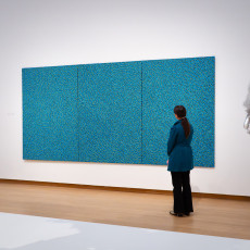 A visitor in front of a turquoise Kusama net painting at the Stedelijk