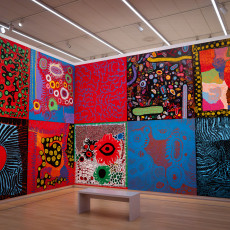 A wall of Kusama's late paintings hung in a grid of bright colours