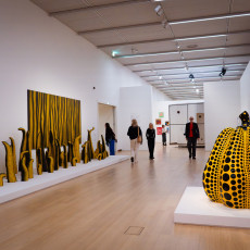 A yellow polka dot pumpkin at the end of a hall lined with tentacle sculptures