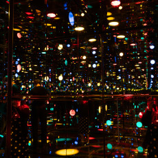 Coloured lights repeating into the distance inside one of the Infinity Mirror Rooms