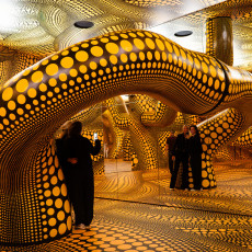 Visitors inside Kusama's yellow tentacle installation, doubled by the mirrored wall