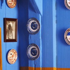 Decorative plates and a framed portrait on a blue plank wall in a Zuiderzeemuseum house interior