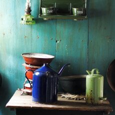 Enamel jug, scales and pans against a green plank wall in a Zuiderzeemuseum kitchen