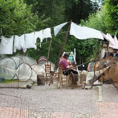 Mending fyke nets under the washing lines on a cobbled square at the Zuiderzeemuseum