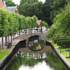 Visitors on the arched brick bridge over the canal in the Zuiderzee Village, Enkhuizen