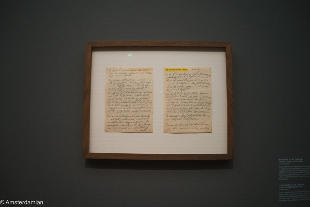 Two pages of a handwritten 1953 letter from Ed van der Elsken, framed on a grey wall with its exhibition label alongside.