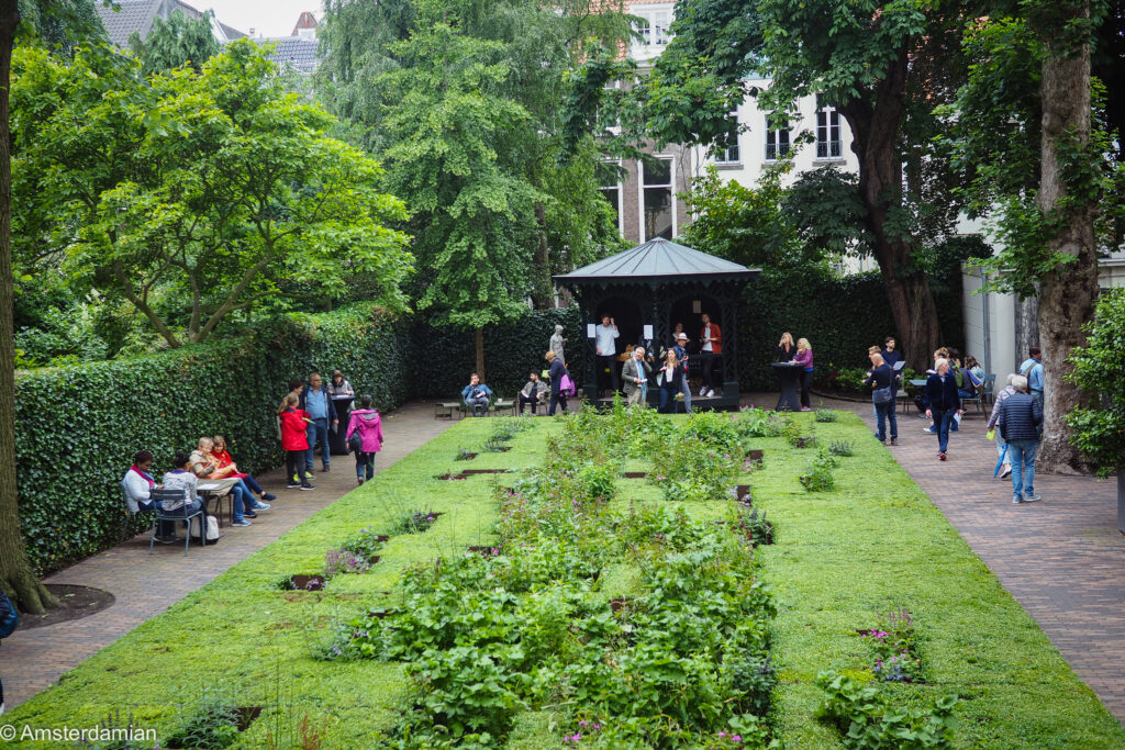 Visitors walking through a long formal canal garden with hedges and a garden pavilion during Open Garden Days Amsterdam