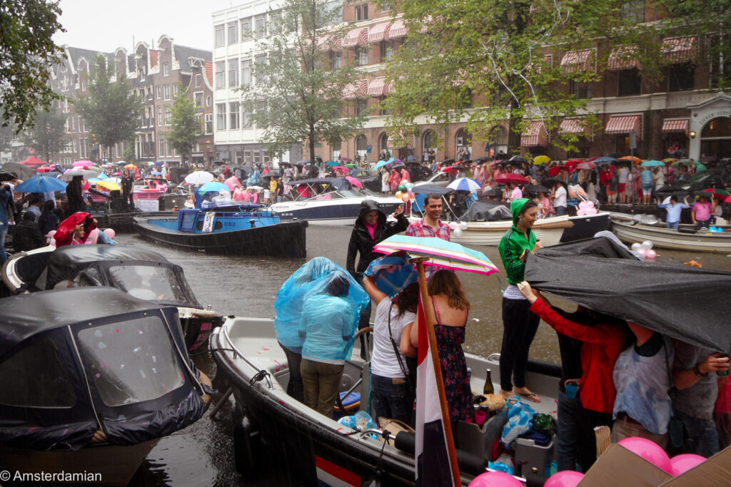 Spectators under umbrellas and rain ponchos watching the Canal Parade in the rain