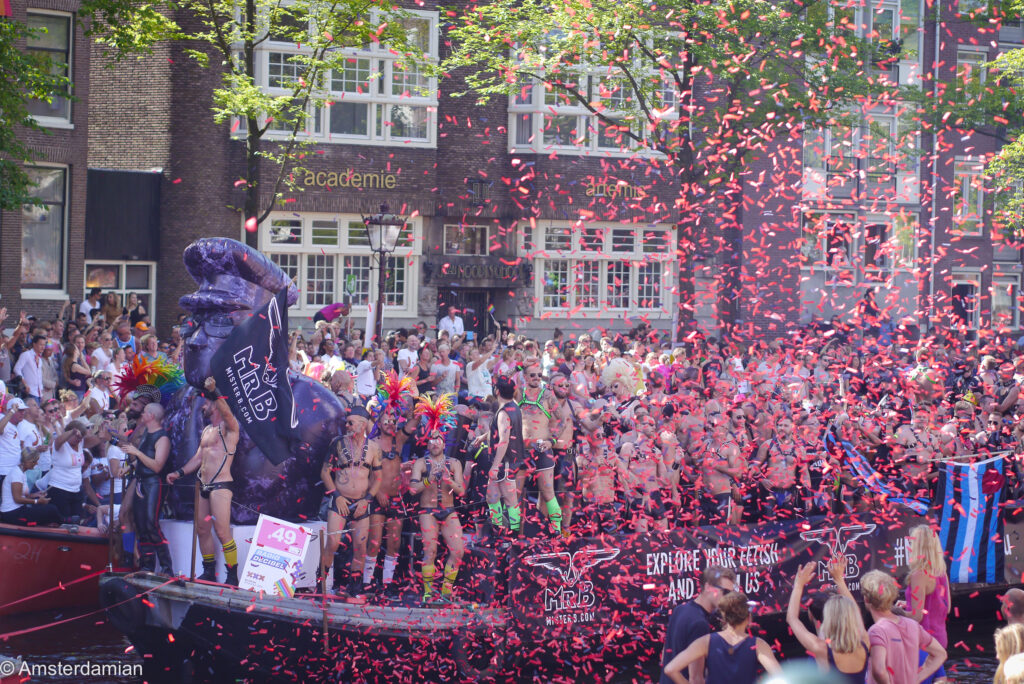 Leather-clad crew of a parade boat in a storm of red confetti at EuroPride 2016