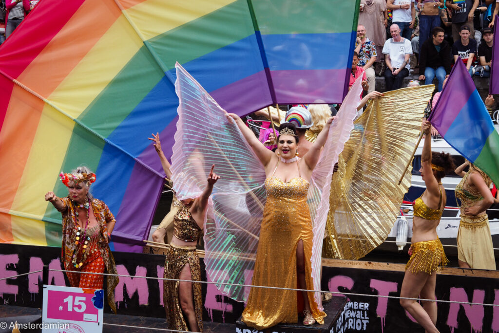 Performers in gold with giant rainbow flags on a boat commemorating the Stonewall riots