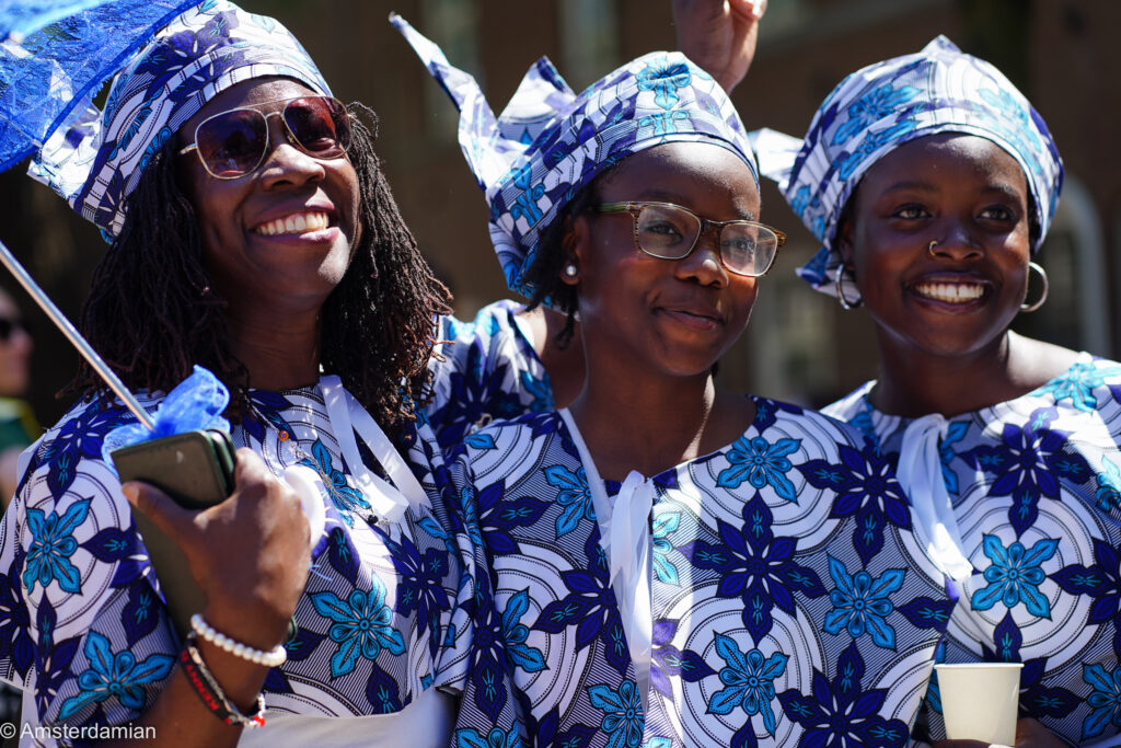 Three women in matching blue-and-white koto dress at the Bigi Spikri parade in Amsterdam
