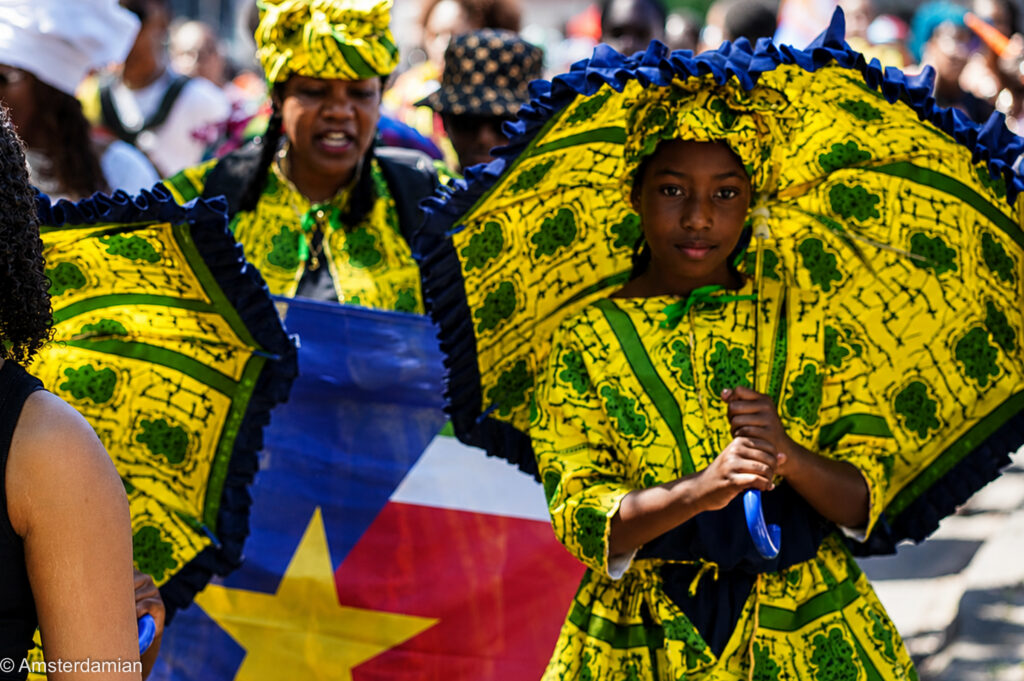 Woman and girl in yellow koto dresses with parasols at Amsterdam's Bigi Spikri parade