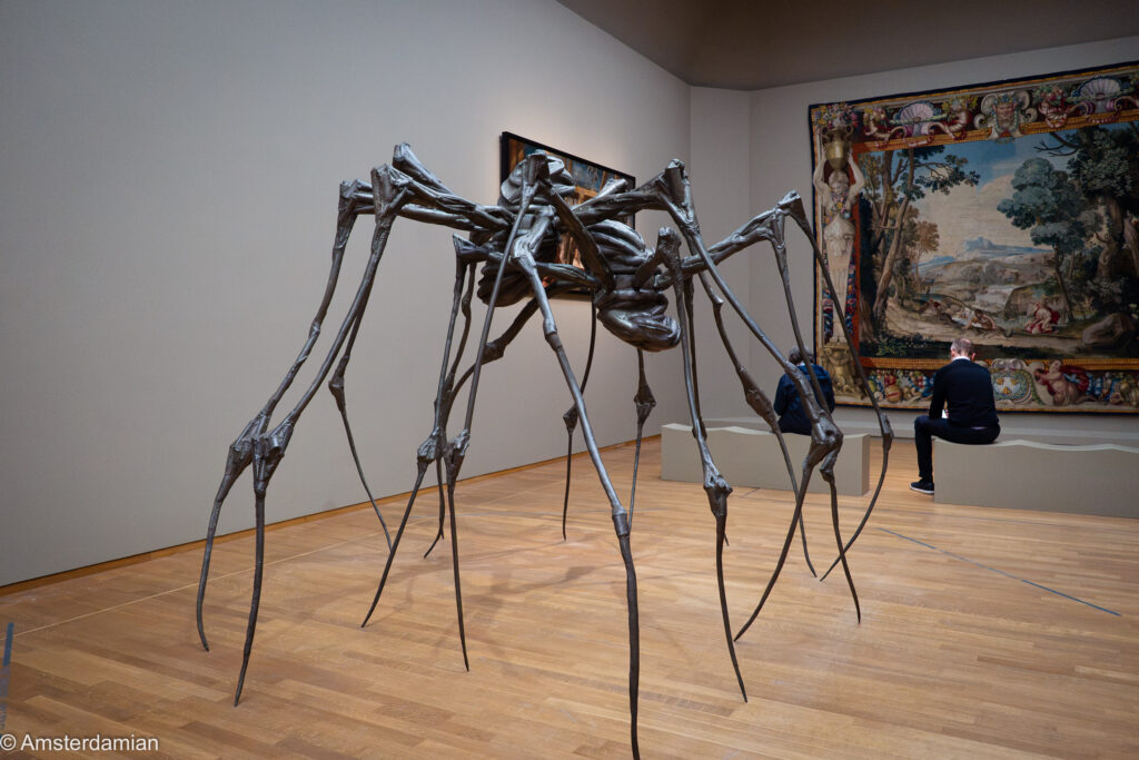 Giant spider sculpture by Louise Bourgeois next to a monumental tapestry at the Rijksmuseum