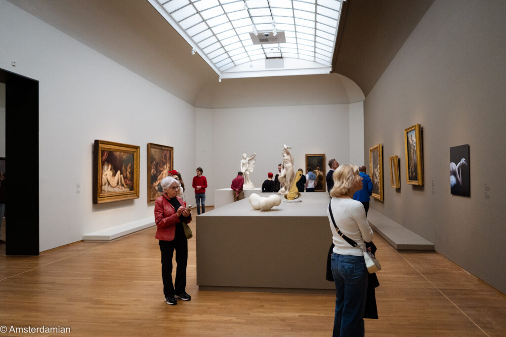 Skylit gallery with mythological paintings and sculptures on a central platform